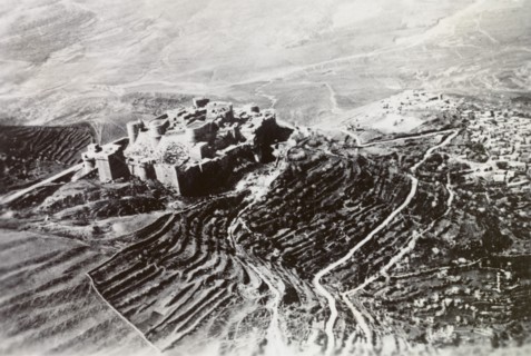 Castle overlooking a Palestinian settlement. An ancient castle with terraced ramparts sits atop a