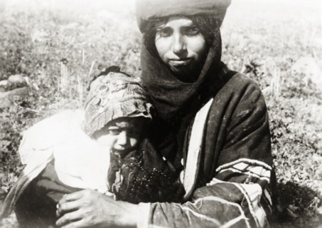 Bedouin mother and child, Palestine. A young bedouin mother cuddles her baby on her lap. British