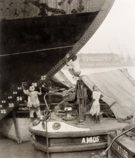 How to paint a ship when you don't have a ladder'. Three dock workers on a river barge attempt to