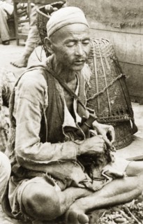 An elderly man at Darjeeling market. An elderly man sits cross-legged at a stall in Darjeeling
