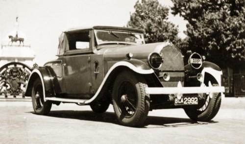 A Hotchkiss 1928, in a rich red'. A 1928 Hotchkiss car, parked outside the gates of the Victoria