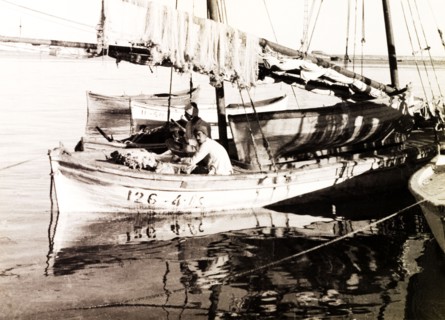 Fishing boat on the Suez Canal. Two fishermen sit aboard a stationary sail boat on the Suez Canal,
