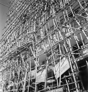 Bamboo scaffolding with adverts, Calcutta. A tall building is encased in bamboo scaffolding as it