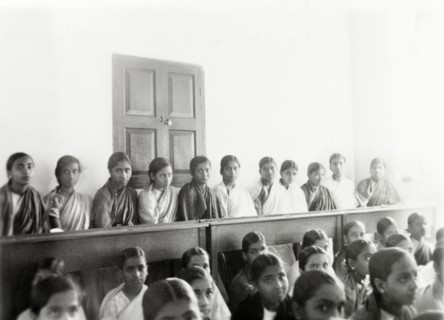 Students at girl's high school, Mysore. Rows of female Indian students sit on benches in a