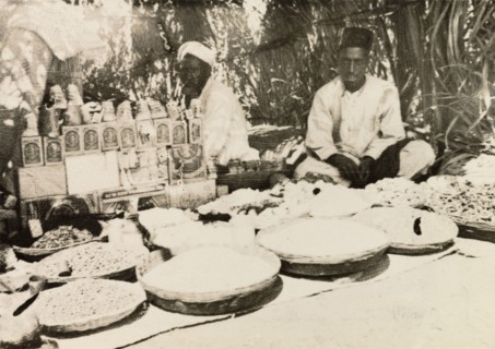 Food stall at Indian market. Two street traders sit in the shade of their covered market stall,