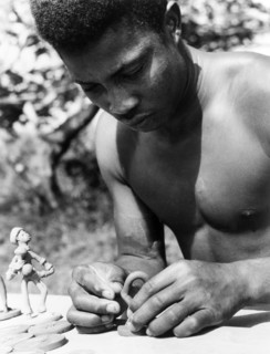 An Antiguan craftsman. A young Antiguan craftsman concentrates as he models small figurines out of