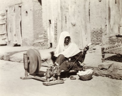 Silk spinner, India. An Indian woman sits by the roadside spinning silk using a 'charkha' or