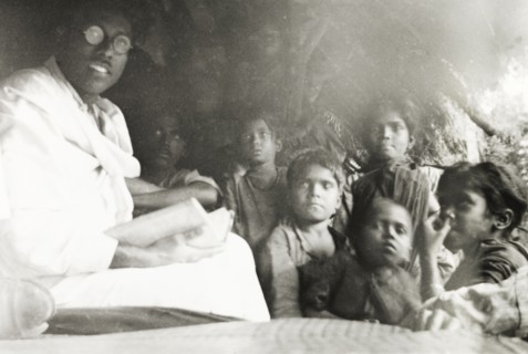Reading to young children, India. A Methodist evangelist reads aloud from a book to a group of