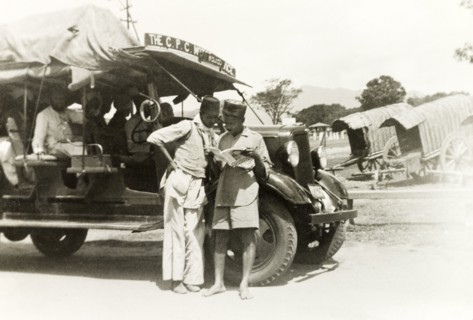 A 'CPS Motor Service' bus. The drivers of a 'CPS Motor Service' bus stand and read a magazine