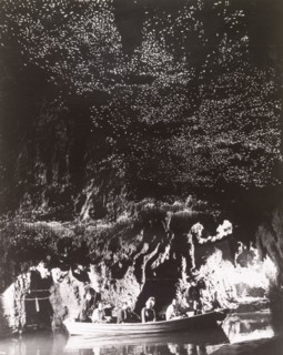 Glow-worm Grotto' at Waitomo Caves. A small tourist boat glides across the still waters of the