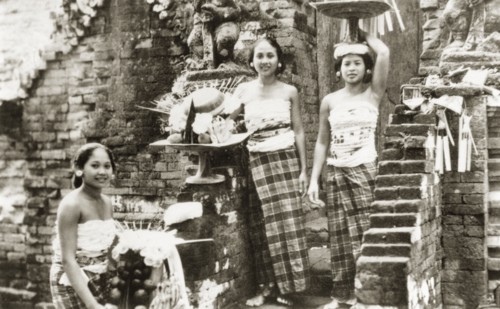 Balinese women posing on temple steps. Three young Balinese women wearing traditional 'kain sarung'