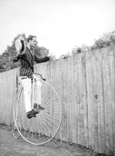 Look, no hands. A woman peers over the top of a tall fence to watch a man in a striped jacket