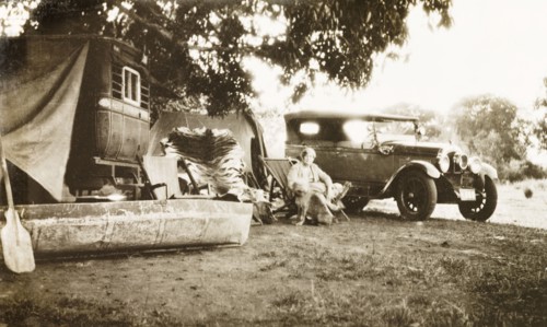 Relaxing at a hunting camp, India. A European woman relaxes in a deckchair with her pet dog at a