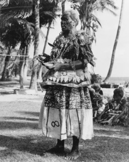 Fijian man with a 'tabua'. A Fijian man wearing face paint and ceremonial costume made from 'masi'