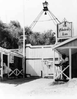 Bolted gate at the Admiral's Inn. A uniformed man leans on a handrail inside a bolted gate. Above