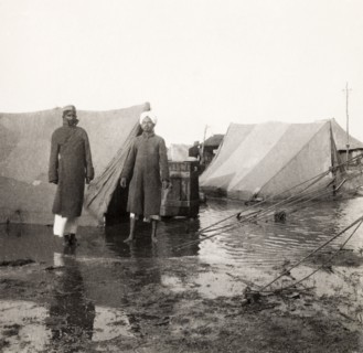 Flood at an Indian Police camp. Two Indian men stand in front of flooded tents at the James