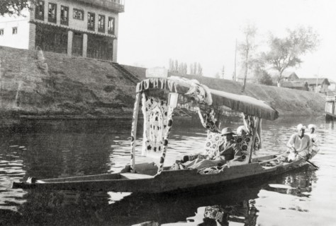 Water taxi on a Srinagar canal. Majid Ullah in the shikari 'Blue Heaven' as he is ferried along a