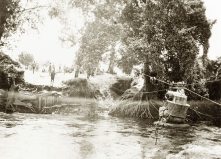 Transporting luggage across a river. A pile of luggage is stacked onto a raft, ready to be hauled