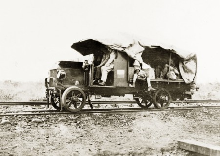 A truck converted to run on rails. Several European men travel in the cab and coach of a truck