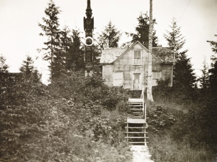 A traditional Tlingit house. A traditional Tlingit house and totem pole, located in a forest on