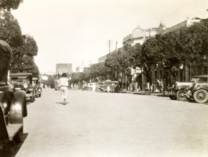 City street in Natal, Brazil. Pedestrians mill about on a wide, tree-lined street in the centre of