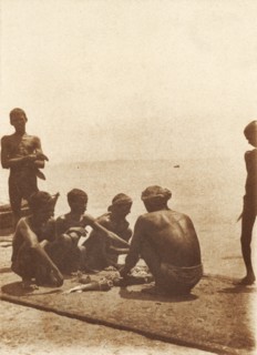 Boatmen on the breakwater. Boatmen cut up fish on the breakwater. Mormugao, Goa, India, circa 1906.