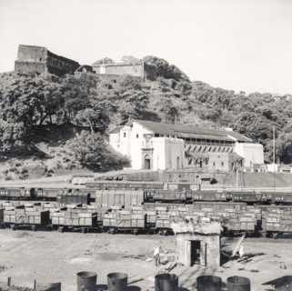 Rail sidings at Mormugao port. Empty freight cars sit on sidings beneath a prominent fortress at