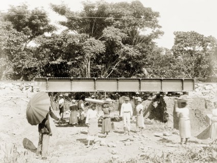 Flood works beneath a railway bridge, Trinidad. Female labourers clear rubble from beneath a