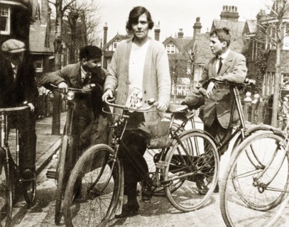Cycling in Eastbourne. Enid Murray and several young men lean on their bicycles on a suburban