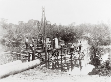 Driving piles into the water. On a wooden scaffolding structure built around a pile driver next to