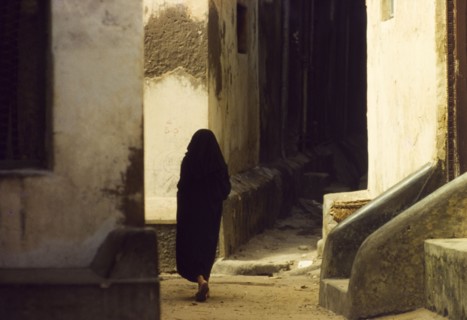 An alleyway in Mombasa. A robed figure walks through a winding alleyway in Mombasa. Mombasa, Kenya,
