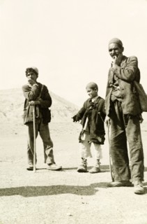 Portrait of an Afghan man and two boys. Dressed in tattered clothes, an Afghan man and two boys