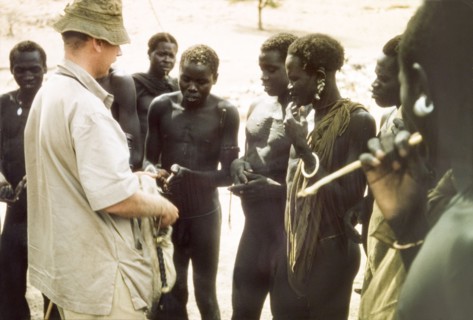 Tobacco exchanged for news. British Game Ranger John Blower offers tobacco to a group of Toposa men