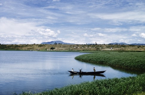 Fishermen in the Kazinga Channel'. Three men in a canoe fish with nets in The Kazinga Channel, half