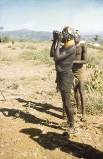 Lotuke with binoculars. Lotuke, a Suk porter working with a British forestry survey team, peers
