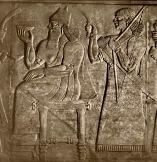 The king, Ashurnasirpal is seated between two attendants