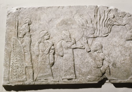 Stone relief depicting Babylonian and Chaldean prisoners in camp, under guard, with a log fire burning behind