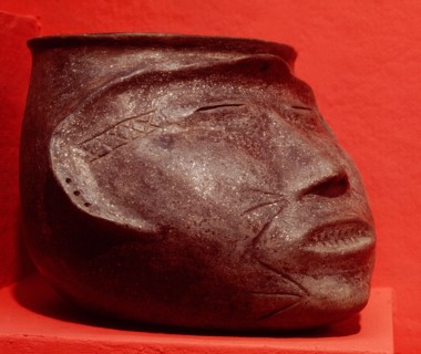 Pottery effigy head vessel representing a trophy head with sealed eyes and mouth sewed shut