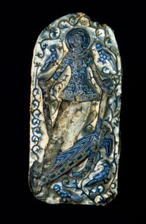A gold and enamel plaque with a figure of a dancing girl