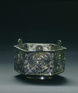 A six sided silver vessel on each side of which is a roundel containing a bust of Christ, the Virgin, Peter, Paul, John and James