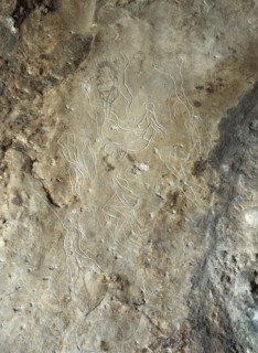 Images of male human figures engraved in limestone walls of the cave at Addaura
