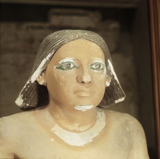 A detail of a statue of a seated scribe showing the head only