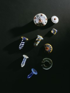 A selection of ear ornaments   glass papyrus column pendants, glazed composition studs and earrings, all worn on wire