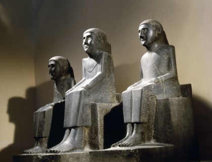 Unusual late Ptolemaic or early Roman carving of three seated figures in a schematic style, from a single block of basalt