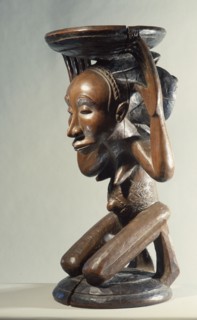 Chiefs stool supported by kneeling woman