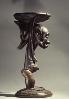 Stool or bowl supported by standing woman