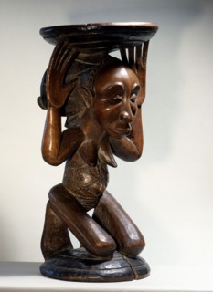 Chiefs stool supported by kneeling woman