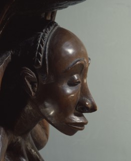 Chiefs stool supported by kneeling woman