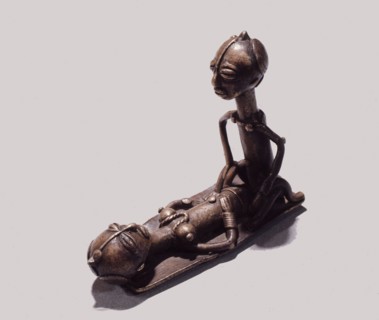 A brass weight which was used for weighing gold dust, representing a man and woman during sexual intercourse