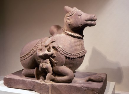 Free standing statue of Nandi, the bull mount of Shiva, with attendant tying a garland around his neck